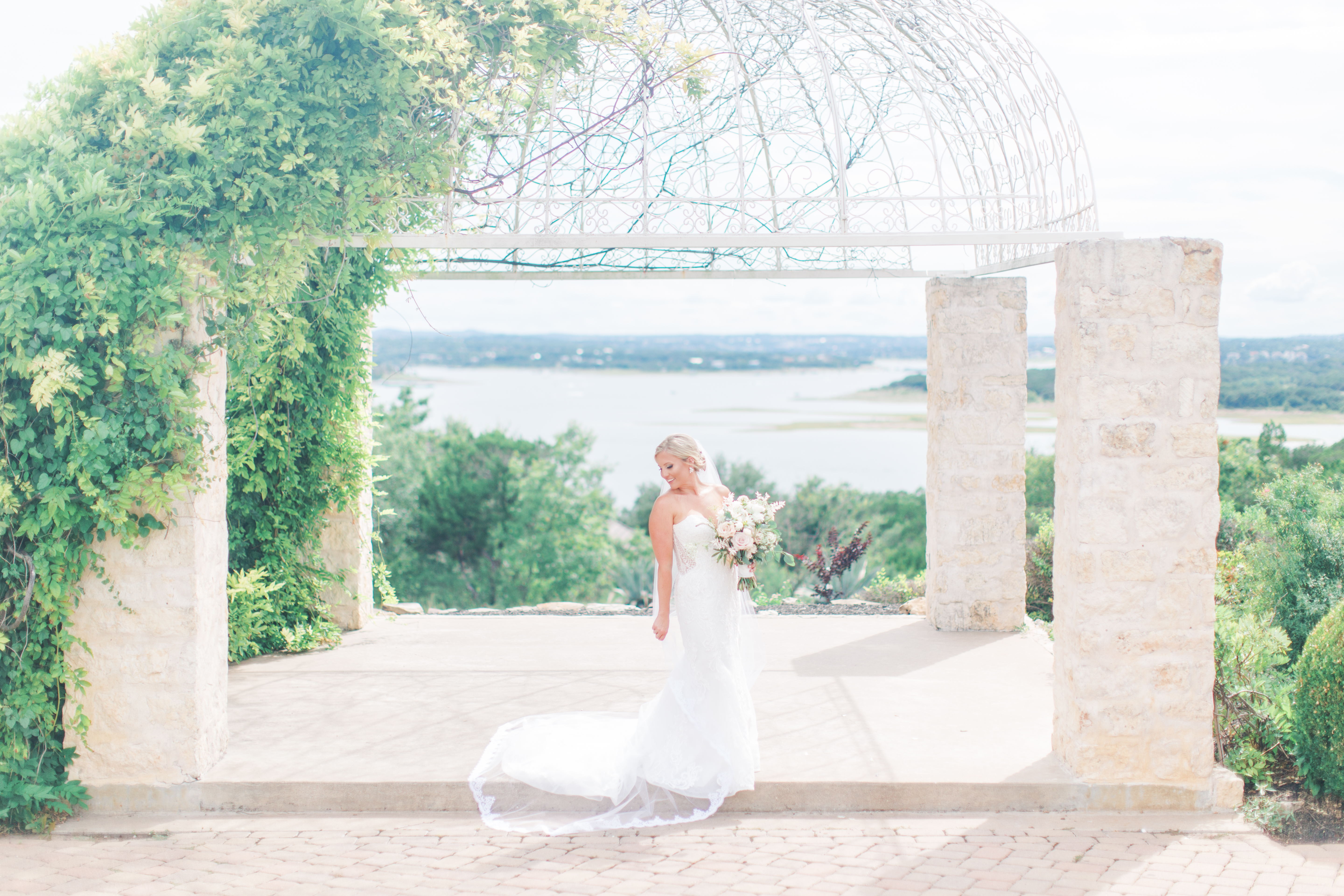 bride standing under white arbor