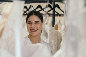 bride looking through rack of wedding dresses